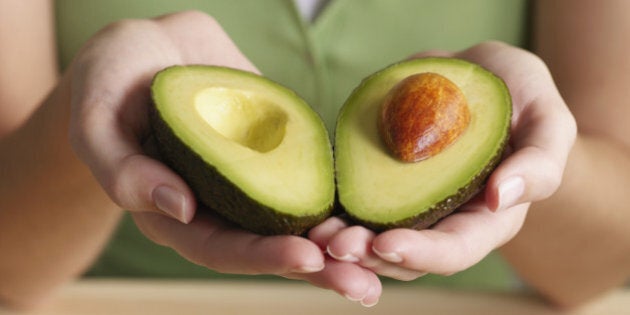 Woman holding halved avocado