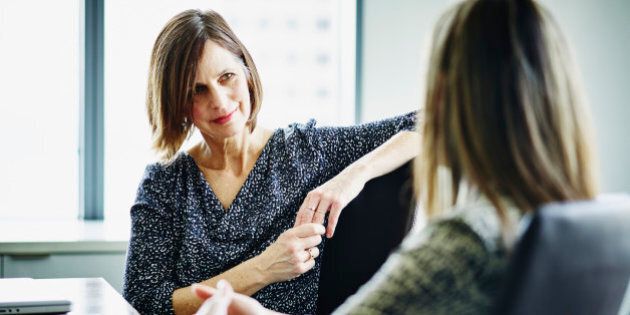 Mature businesswoman in discussion with female colleague at conference table in office