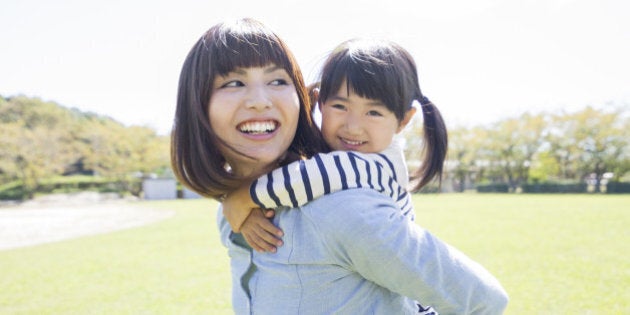 Close-up Of A Mother Giving Piggyback Ride To Her Smiling Daughter