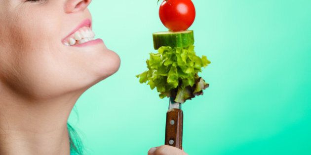 Healthy eating and diet concept. Closeup happy young woman holding vegetables on green blue background. Studio shot.