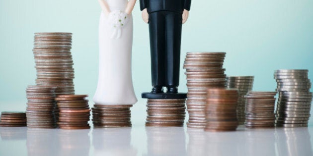 Close up of wedding cake figurines on stacks of coins