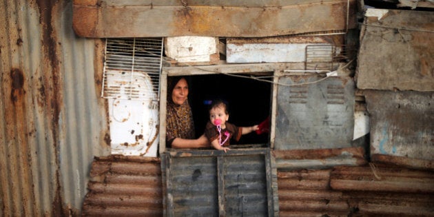 A Palestinian woman and her child look out of the window of their shelter in Deir al-Balah refugee camp in the central Gaza Strip July 29, 2016. REUTERS/Mohammed Salem