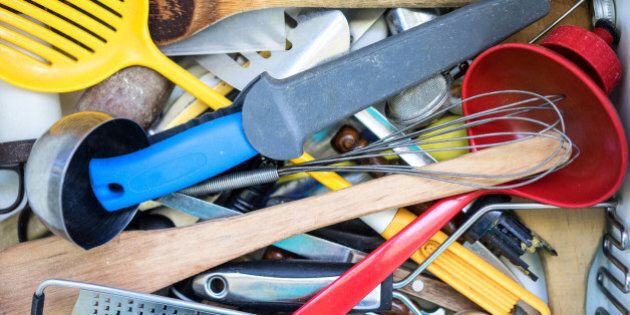Untidy clutter of kitchen utensils in a drawer.