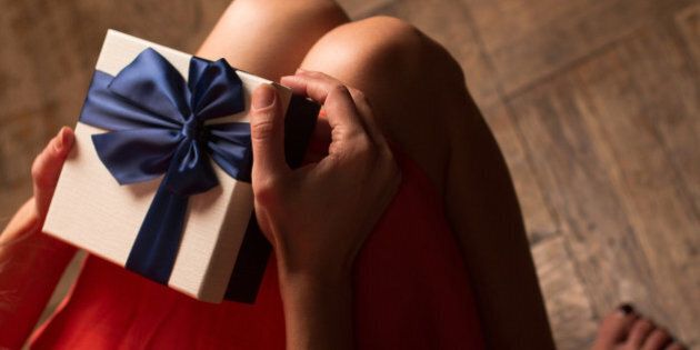 Top view woman with red dress holding a gift box with blue ribbon on her knees