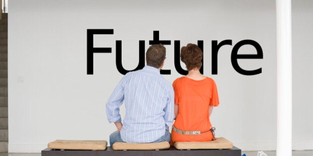 Rear view of couple seated on bench reading English text on wall