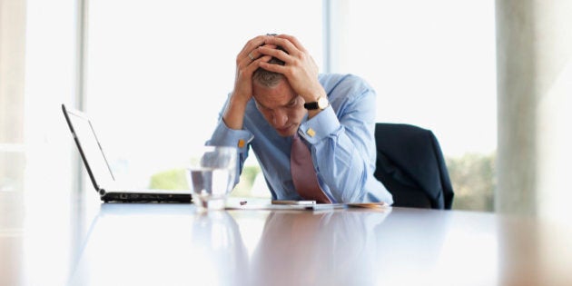 Frustrated businessman with head in hands at desk