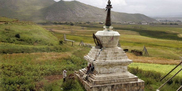 A woman stands in front of a Tibetan Buddhism ritual monument in Shangri La County, in northwestern Yunnan province Saturday Aug. 26, 2006. Shangri La village, is a popular tourist destination to visit the mythical land of