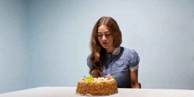 Woman sitting at table, looking at cake