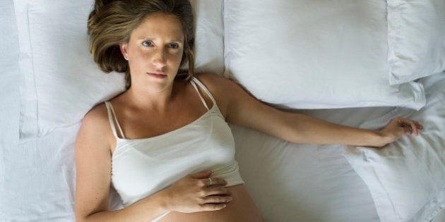Pregnant woman lying in bed alone