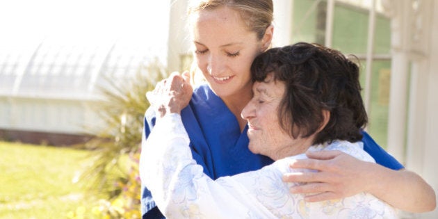 Young female nurse and senior woman embracing.