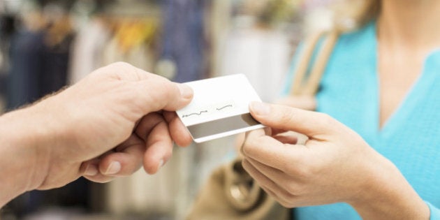 Female customer giving credit card at cash counter to salesperson. Horizontal shot.