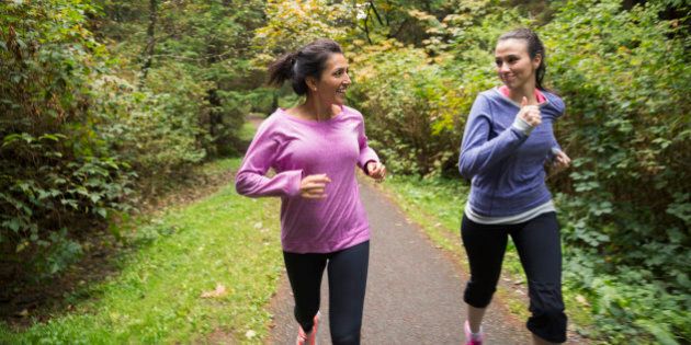 Mother and daughter jogging on path in woods