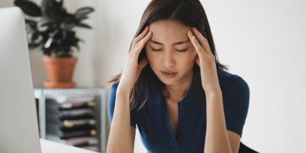 Young businesswoman suffering from headache at desk in office