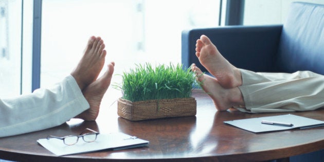 Two businesswomen resting feet on coffee table, low section, side view