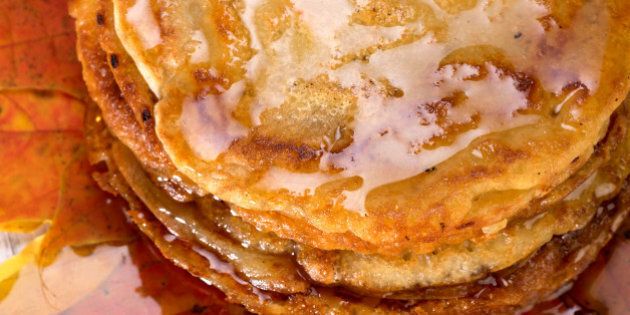 pancakes topped with maple syrup lie on autumn maple leaves