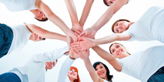 Teamwork concept. Group of women joining hands. Low angle view, white background.