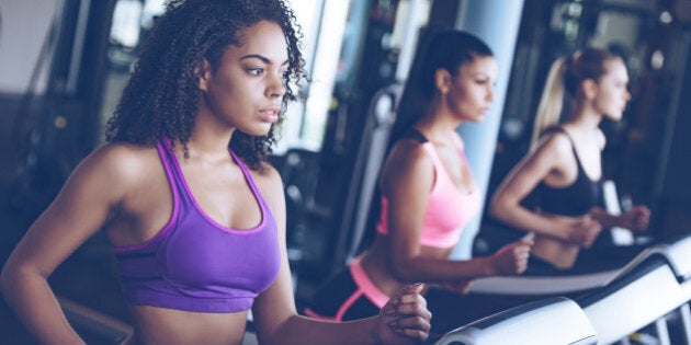 Side view close up of young beautiful women looking away while running on treadmill at gym