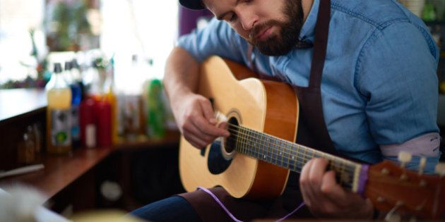 Bearded bartender playing guitar