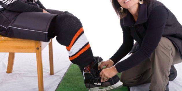 Mother tying sons hockey skates
