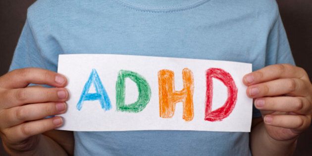 Young boy holds ADHD text written on sheet of paper. ADHD is Attention deficit hyperactivity disorder. Close up.