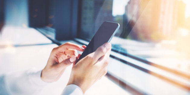 Girl touching a screen of her smarthone. Blurred background