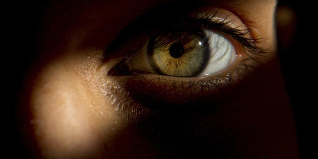 Detail of woman's eye, peering through door slat