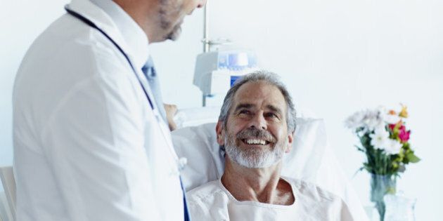 Happy mature patient looking at male doctor in hospital ward