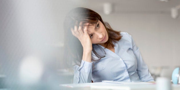 Tired businesswoman with head in hands looking away