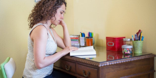 A beautiful young woman reading a book and relaxing in a reading nook