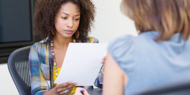 African American woman reading a resume while taking interview of a Caucasian woman