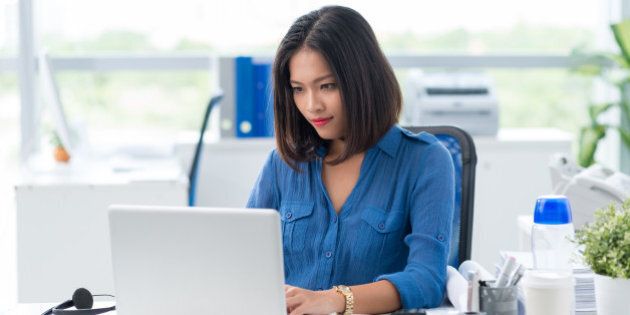Concentrated businesswoman tying on laptop in office