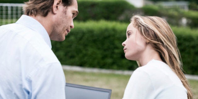 Father and daughter discussing over laptop at yard