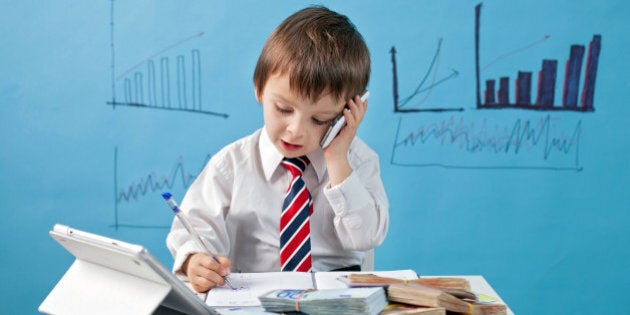 Young boy, talking on the phone, taking notes, money and tablet on the table