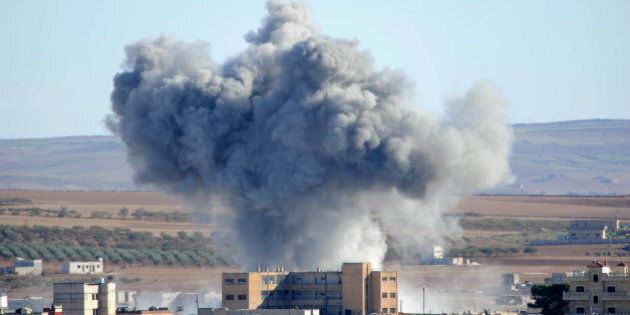 SANLIURFA, TURKEY - OCTOBER 20: (TURKEY OUT) Heavy smoke from an airstrike by the U.S.-led coalition planes rises in Kobani, Syria, October 20, 2014 as seen from a hilltop on the outskirts of Suruc, at the Turkey-Syria border, in Sanliurfa province, Turkey. According to Foreign Minister Mevlut Cavusoglu, Turkey will reportedly allow Iraqi Kurdish fighters to cross the Syrian border to fight Islamic State (IS) militants in the Syrian city of Kobani while the United States has sent planes to drop weapons, ammunition and medical supplies to Syrian Kurdish fighters around Kobani. (Photo by Gokhan Sahin/Getty Images)