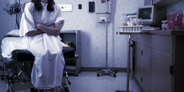 a caucasian female patient in a hospital gown sits in an exam room and waits