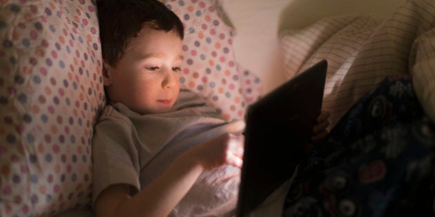 USA, New Jersey, Jersey City, Boy (6-7) using digital tablet in bed