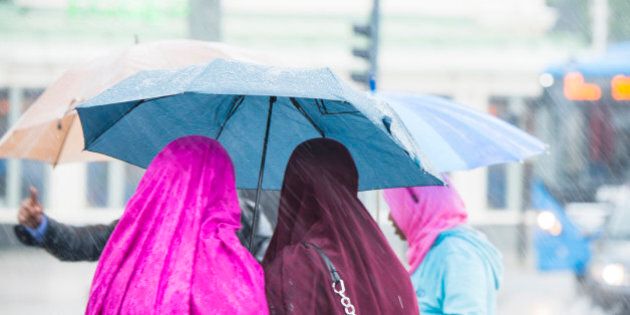 Women wearing headscarves under umbrella
