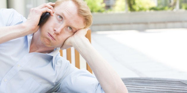 Closeup portrait, worried young man in blue shirt talking on phone to someone, looking up, isolated outdoors outside background