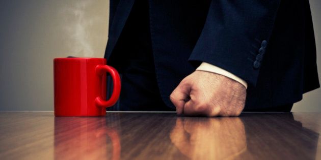 Close-up of Businessman Hitting Desk with Fist Beside Coffee Cup