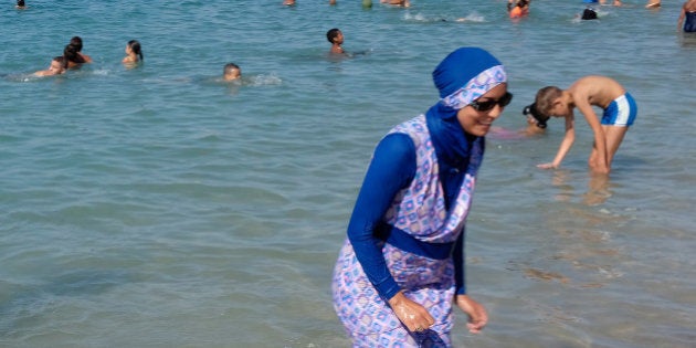 A woman wearing a burkini walks in the water August 27, 2016 on a beach in Marseille, France, the day after the country's highest administrative court suspended a ban on full-body burkini swimsuits that has outraged Muslims and opened divisions within the government, pending a definitive ruling. REUTERS/Stringer