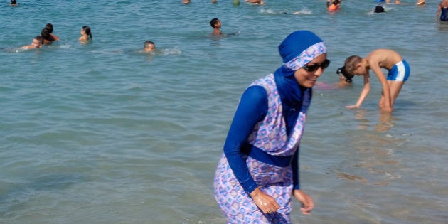 A woman wearing a burkini walks in the water August 27, 2016 on a beach in Marseille, France, the day after the country's highest administrative court suspended a ban on full-body burkini swimsuits that has outraged Muslims and opened divisions within the government, pending a definitive ruling. REUTERS/Stringer