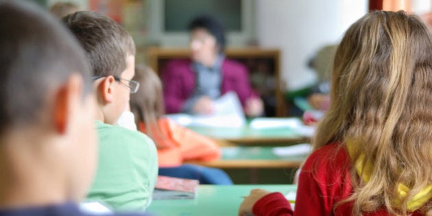 Kids in classroom studying, photographed from behind