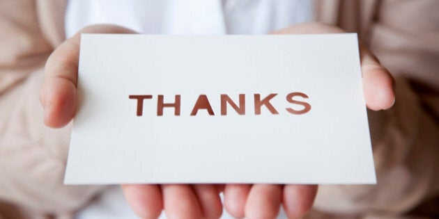 a woman holding a card with a message, THANKS, written on it.