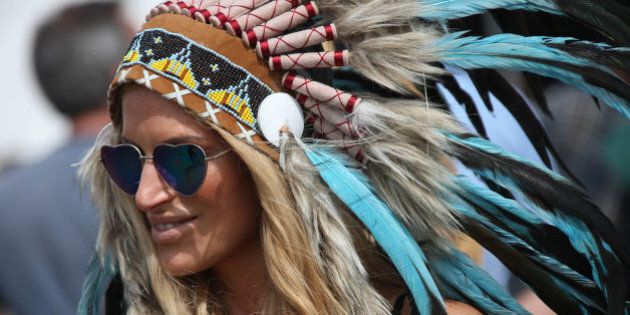 A music lover with heart-shaped sunglasses and a feathered headdress passes through Glastonbury Music Festival on Saturday, June 27, 2015 at Worthy Farm, Glastonbury, England. (Photo by Joel Ryan/Invision/AP)