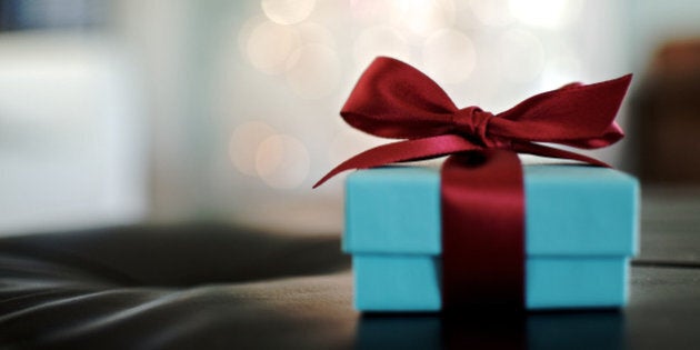 Aqua jewelry box with red satin bow with Christmas tree lights sparkle in background.