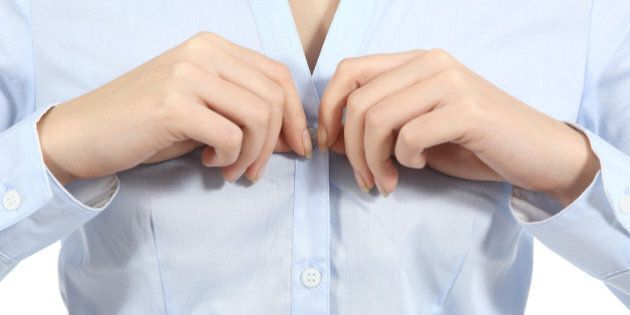 Closeup of a woman hands unbuttoning a shirt isolated on a white background