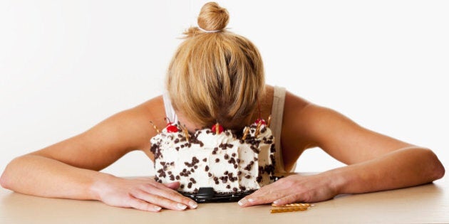 Stidio shot of woman with face in birthday cake