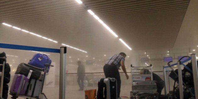 In this photo provided by Ralph Usbeck an unidentified traveller gets to his feet in a smoke filled terminal at Brussels Airport, in Brussels after explosions Tuesday, March 22, 2016. Authorities locked down the Belgian capital on Tuesday after explosions rocked the Brussels airport and subway system, killing a number of people and injuring many more. Belgium raised its terror alert to its highest level, diverting arriving planes and trains and ordering people to stay where they were. Airports across Europe tightened security. (Ralph Usbeck via AP)