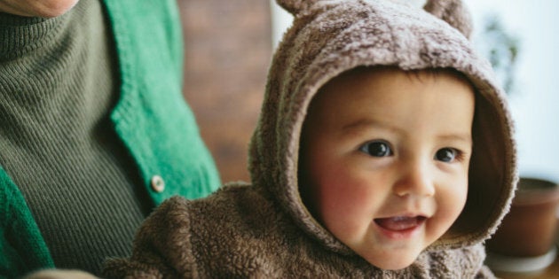 Cheerful mixed race baby girl wearing a bear costume.