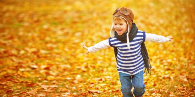 happy child playing pilot aviator and dreams outdoors in autumn